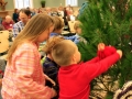 Children, youth and parents decorating the Mitten Tree with hats, scarves, gloves and mittens.
