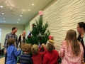 Children, youth and parents decorating the Mitten Tree with hats, scarves, gloves and mittens.