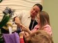 Children, youth and parents decorating the Mitten Tree with hats, scarves, gloves and mittens.