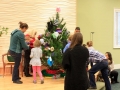 Children, youth and parents decorating the Mitten Tree with hats, scarves, gloves and mittens.