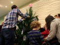 Children, youth and parents decorating the Mitten Tree with hats, scarves, gloves and mittens.